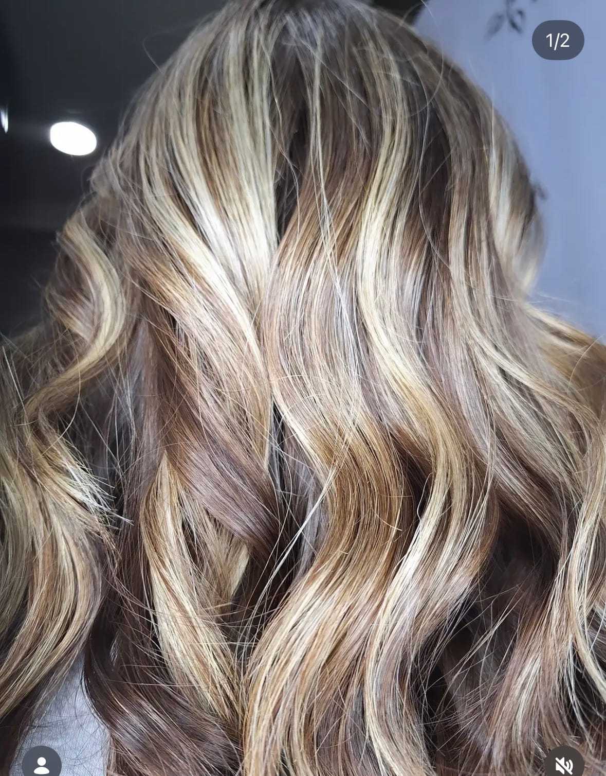 Long, wavy hair with blonde highlights, styled in soft curls.