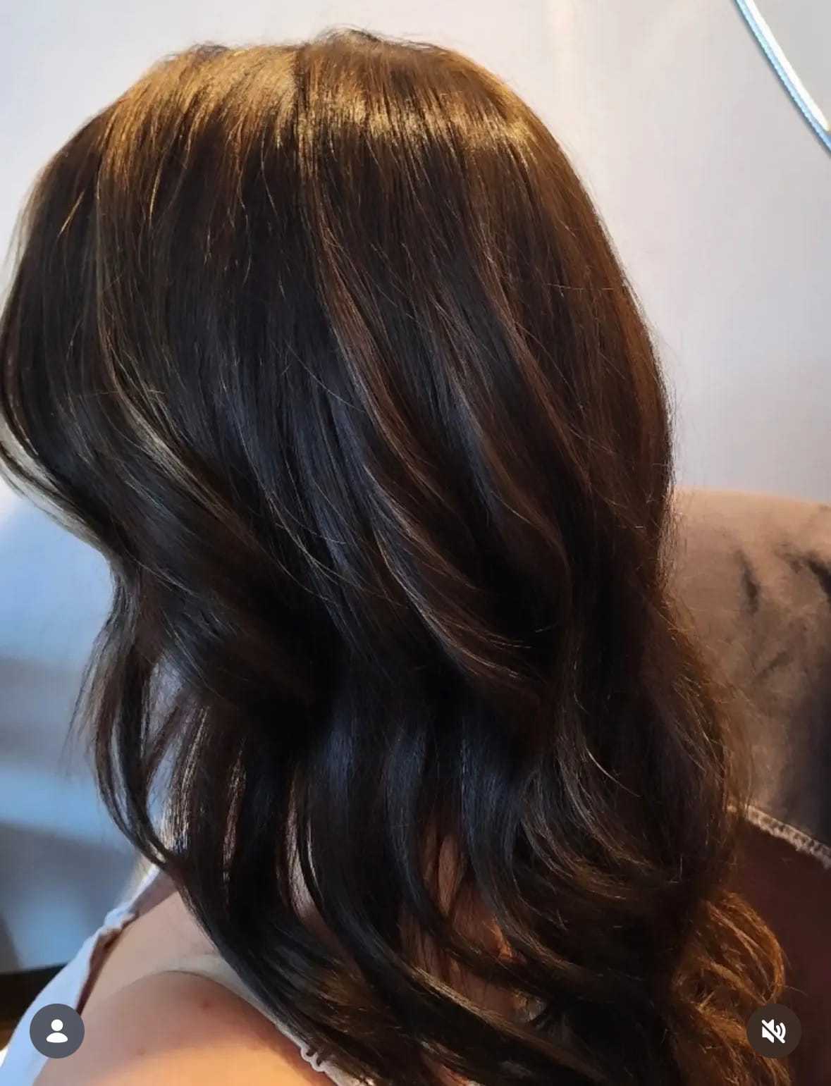 Close-up of a woman's brunette hair with soft waves, photographed indoors.