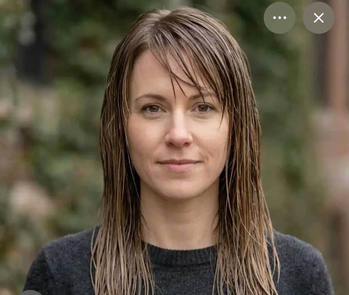 Woman with wet hair and a neutral expression standing outdoors.