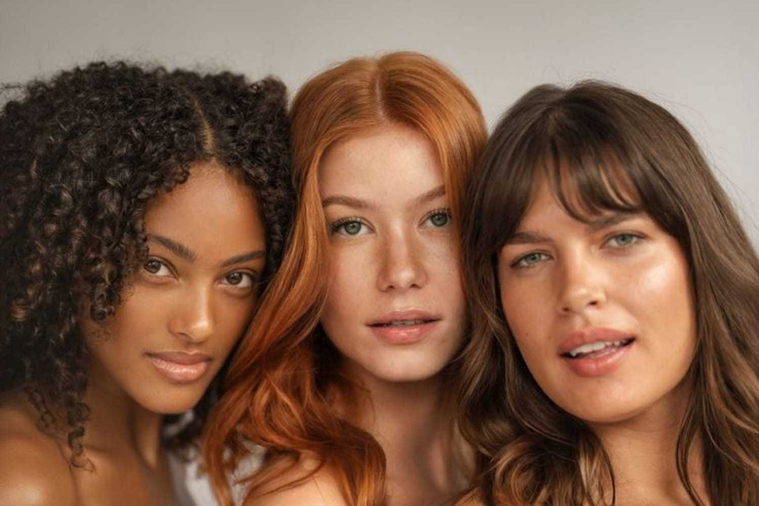 Three women with diverse hairstyles posing together closely.